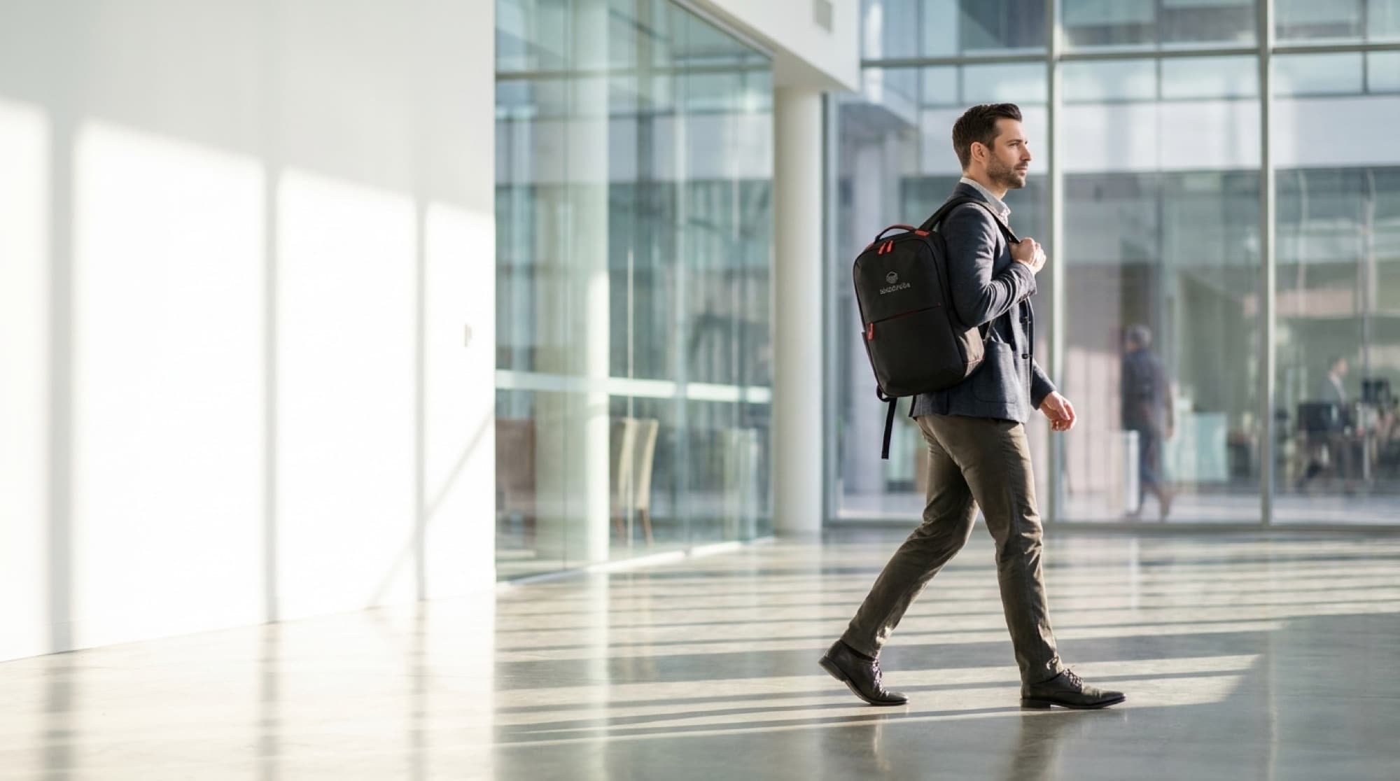 Team member walking through a bright office lobby carrying a custom branded backpack